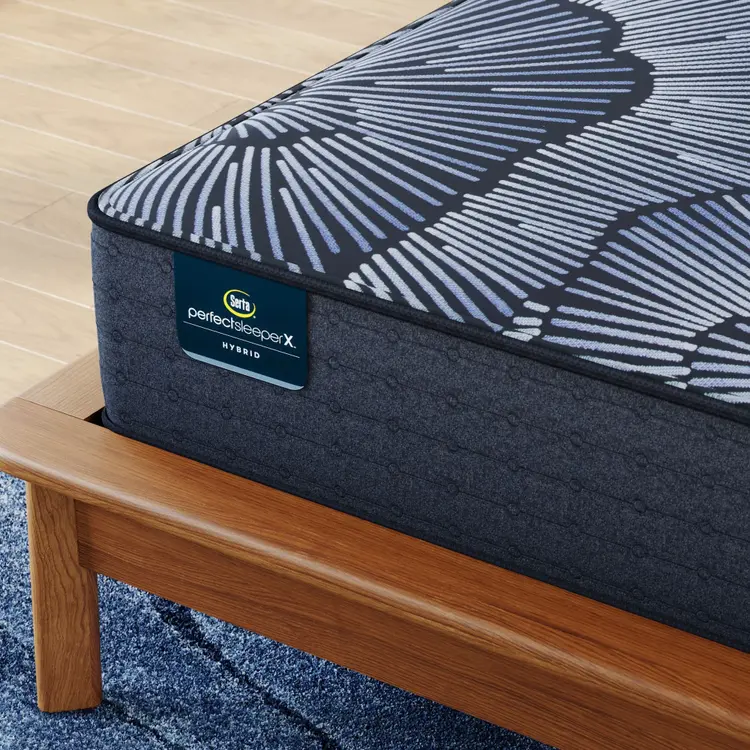 Corner of Perfect Sleeper X Hybrid Aspen Firm Mattress sitting in a brown bedframe || feel: firm || level: Level 1