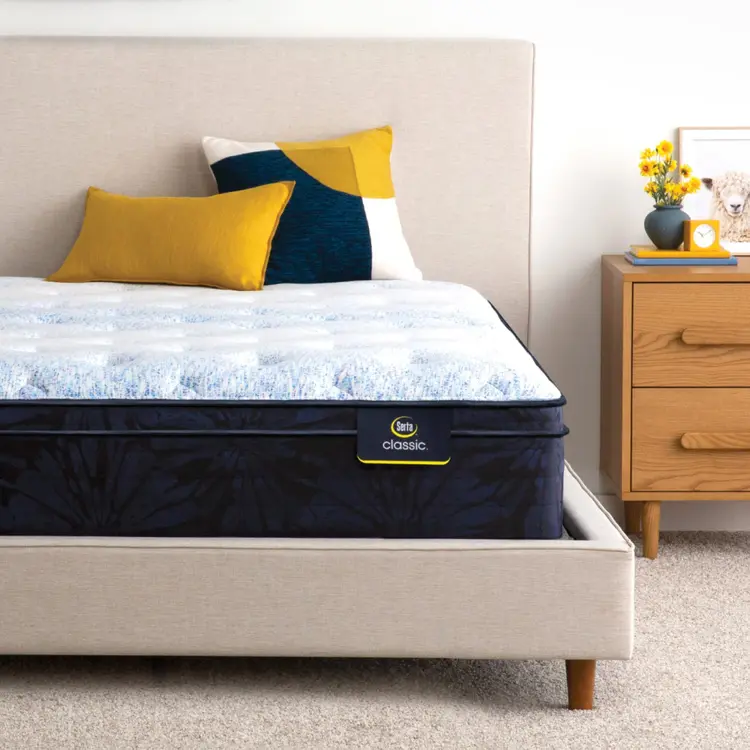 Serta classic dorian plush euro top mattress sitting in a beige bed frame ||feel: plush euro top||level: standard